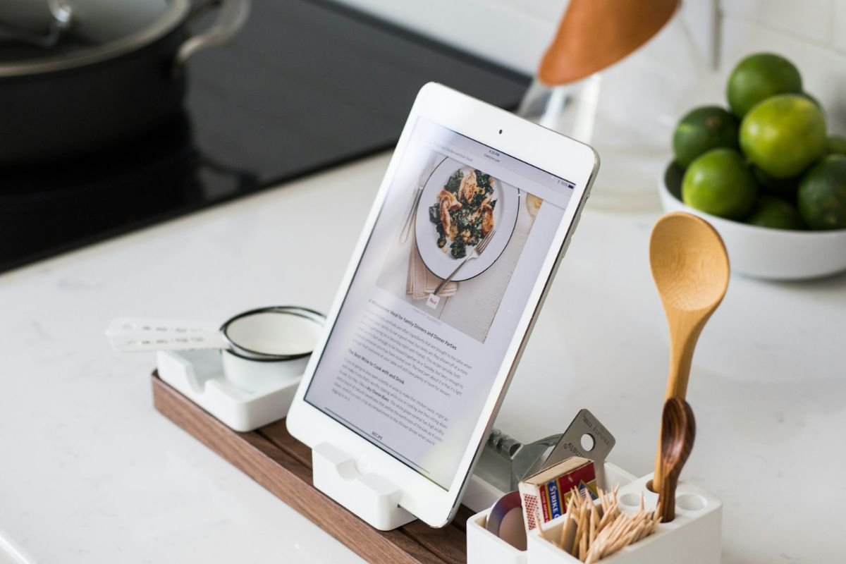 Cooking with Technology A tablet displaying a recipe on a kitchen counter, surrounded by kitchen utensils and ingredients.