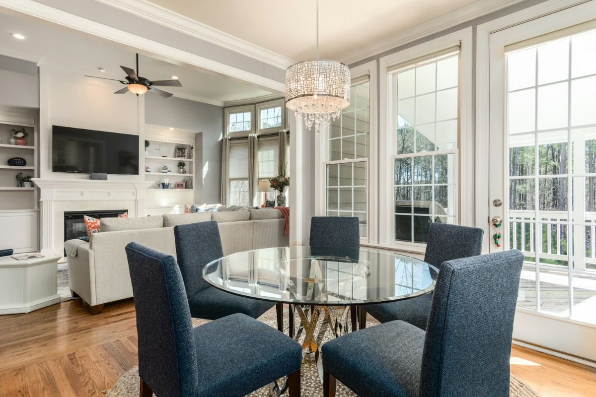 Tidy Living and Dining Space with Modern Design A tidy, bright and modern open living and dining room with a chandelier, a glass dining table, and a cosy sofa area.