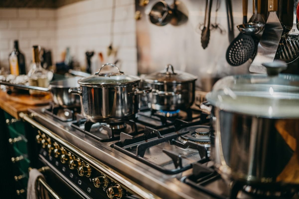 Close-up of a kitchen stove with multiple pots cooking on gas burners.