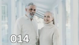An older couple with joyful expressions sitting outdoors, embracing each other while basking in natural light.