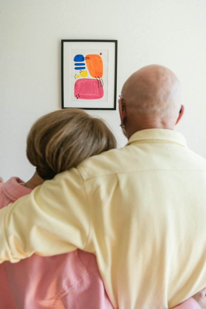 Mastering the Art of Love: A Lifelong Connection An older couple embraces while admiring a piece of artwork, reflecting a lifetime of shared experiences and deep connection.