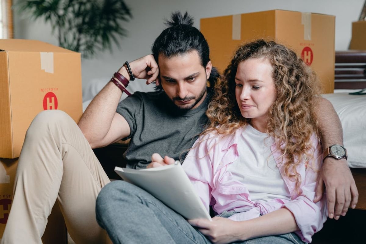 Couple Reflecting on Qualities of Love and Partnership A couple sat on the floor of their home. The woman writes a checklist of partner qualities while the man reads it thoughtfully.