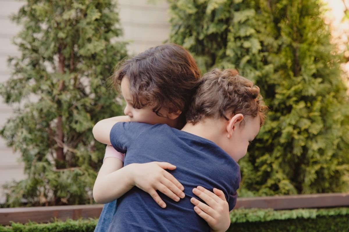 Young boy and girl hugging each other warmly, symbolising forgiveness and reconciliation.