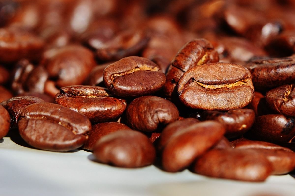 Rich Roasted Coffee Beans: The Aroma of Quality Brewing Close-up of roasted coffee beans spilling onto a wooden surface.