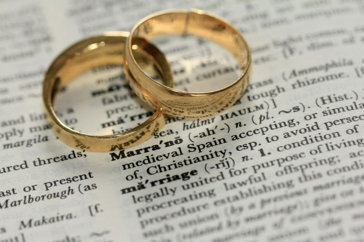 Gold Rings and the Meaning of Marriage Two gold wedding rings rest on an open dictionary, highlighting the word 'marriage' and its definition, symbolising the union and commitment it represents.