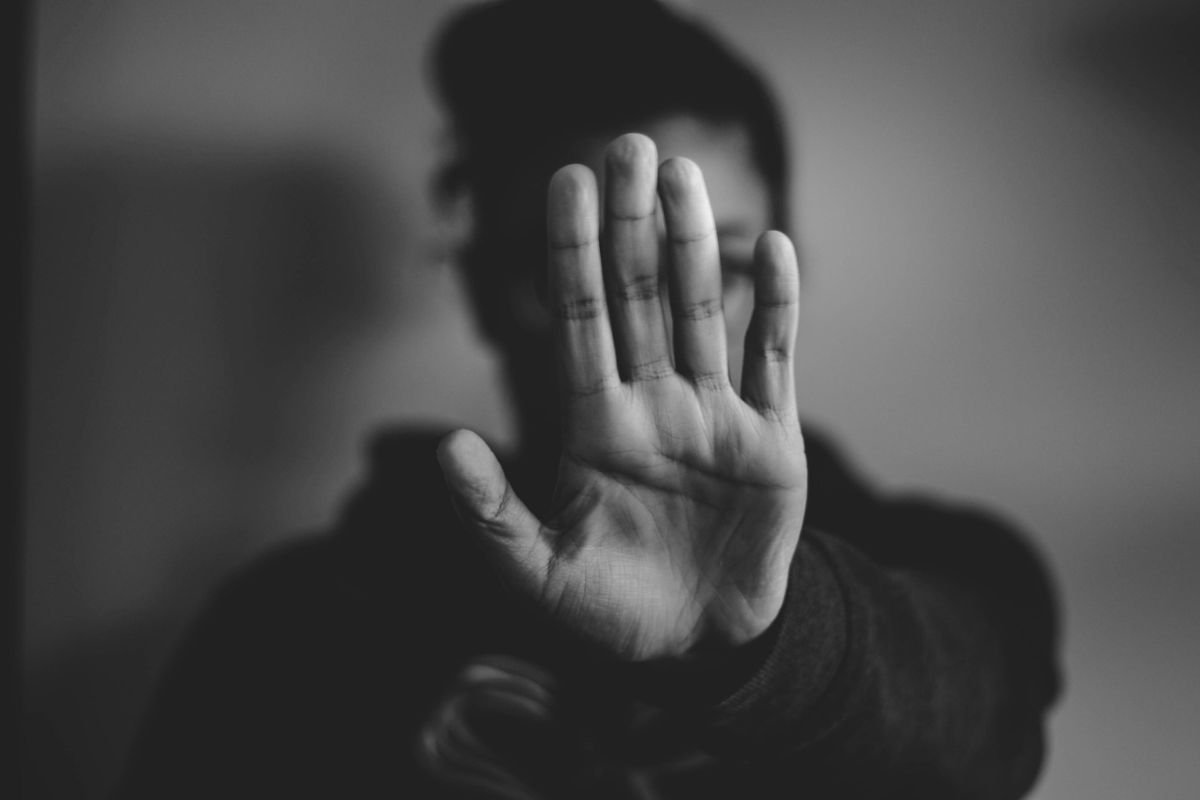 Close-up of hands raised against a cloudy sky in a hopeful gesture.