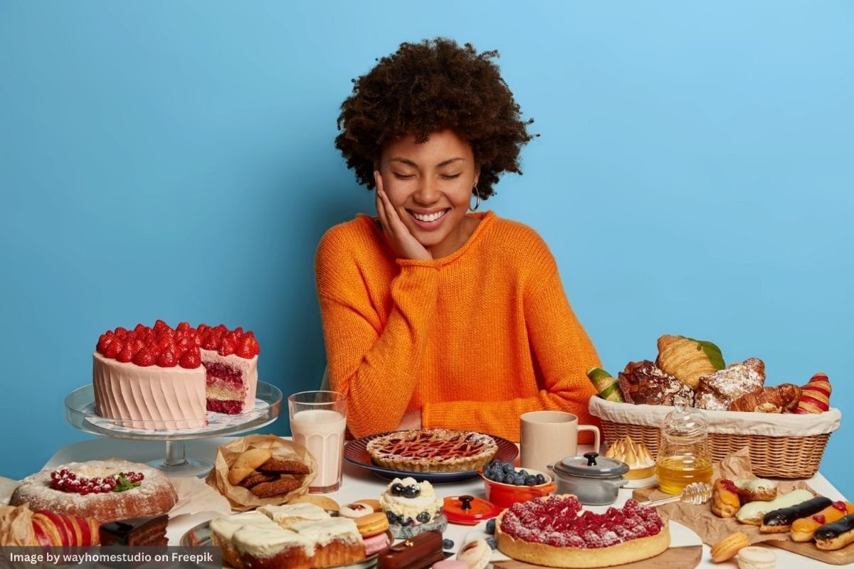 A cheerful young woman looking forward to satisfying her sugars cravings by indulging in cakes, pastries, and desserts.