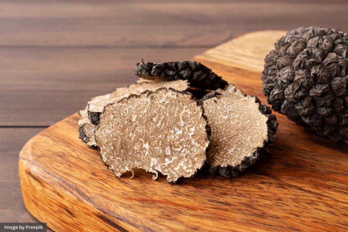 The Truth About Truffles: Real or Replica? High-angle view of sliced truffles on a rustic wooden surface, showcasing the intricate patterns and textures of the rare fungi.