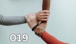 Close-up of diverse hands joined together on a white background, symbolising unity and connection.