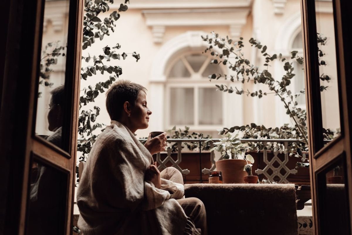 A woman sipping tea on a balcony, looking serene and contemplative as she reflects on her true life priorities.