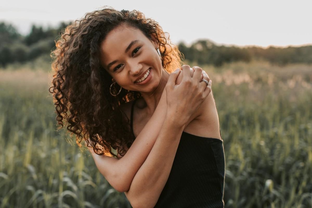 Woman Hugging Herself as a Symbol of Self-Kindness A woman wearing a black top hugging herself, symbolising self-compassion and the importance of being kind to oneself.