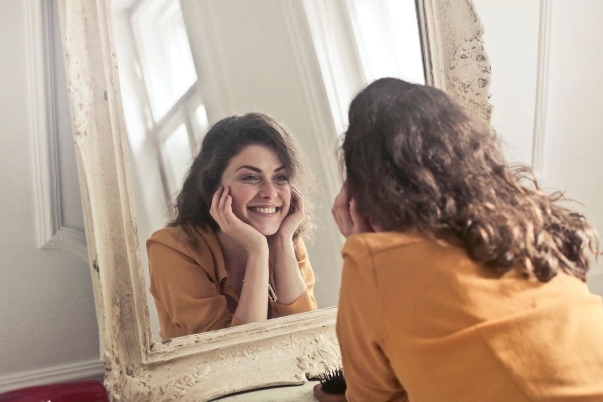 Woman Reflecting on Herself in a Mirror A woman looking at her reflection in the mirror, symbolising introspection and self-awareness.