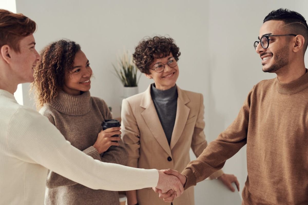 Confident Greeting and Warm Welcome in a Social Setting A group of people warmly welcoming and greeting a man with confident body language in a lively social setting.