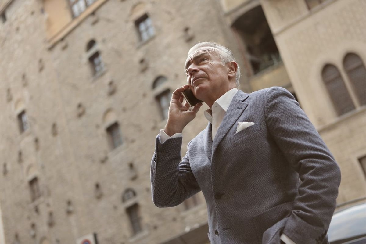 Confident Businessman in Gray Suit Holding a Smartphone A man in a gray suit confidently checking his smartphone in a professional environment.