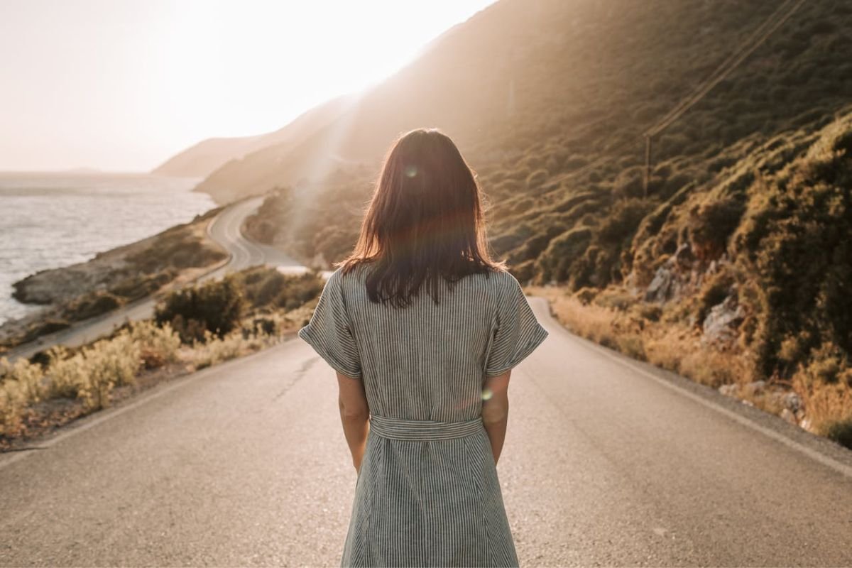 A woman in a blue and white dress standing confidently in the middle of an empty road, symbolising freedom and self-determination.