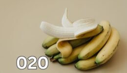 A peeled banana resting on a light surface with visible texture on the fruit's flesh.