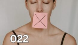 A woman with a yellow sticker note displaying a black X on her mouth, symbolising the importance of silence and discretion.