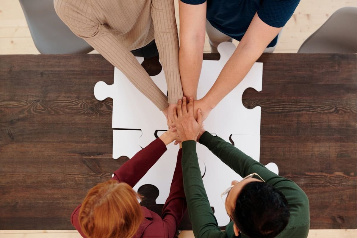 Group Joining Hands: Understanding the Principle of Liking A group of people joining hands, symbolising trust, connection, and the principle of liking in social psychology.
