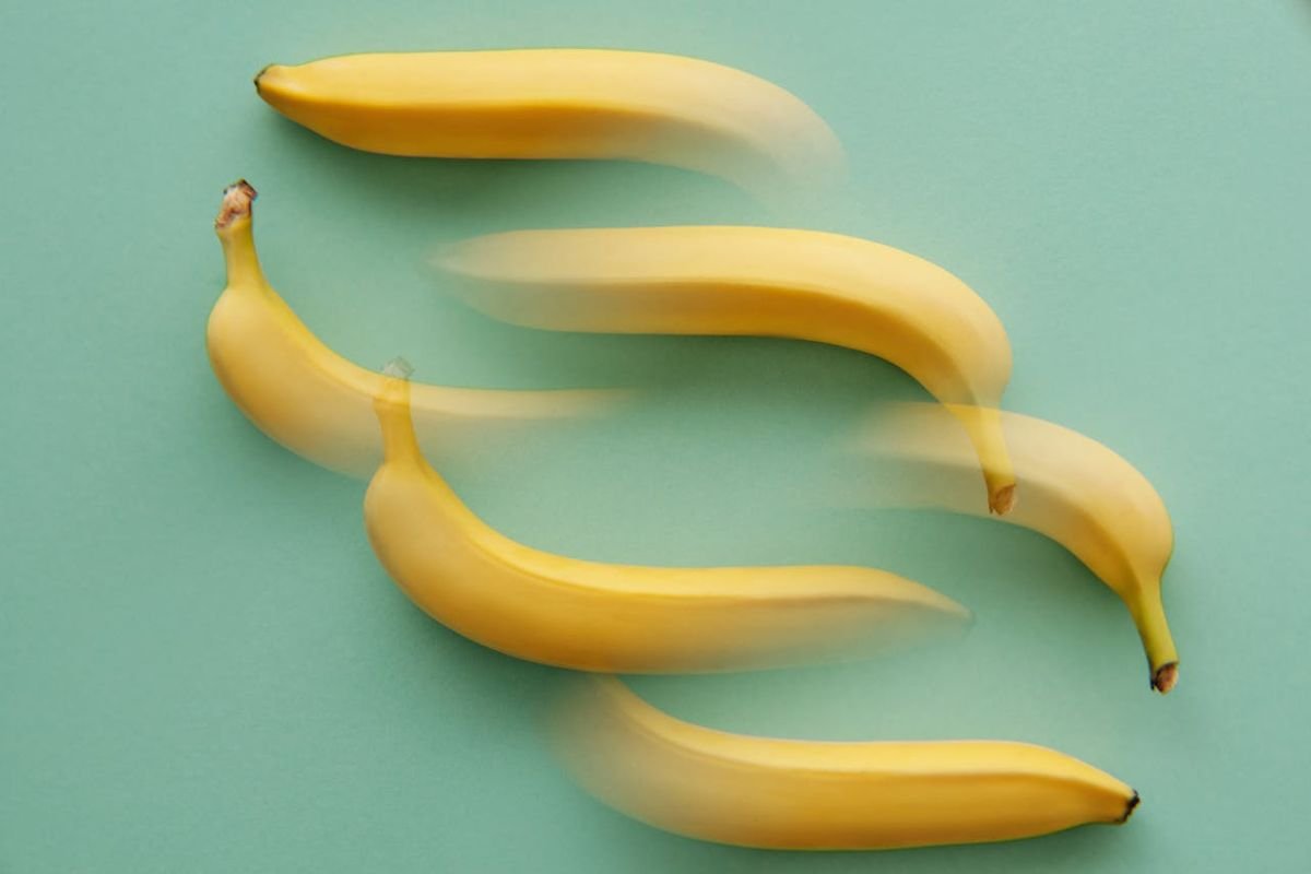 Vanishing Bananas: A Conceptual Look at a Disappearing Staple A conceptual image of partially faded yellow bananas on a green surface, symbolising the potential disappearance of beloved banana varieties.
