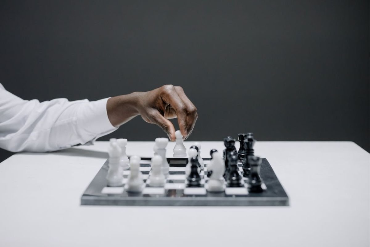 Strategic Moves: Manipulation Illustrated Through Chess A close-up of a chessboard with a hand strategically moving a chess piece, representing manipulation and strategic influence.