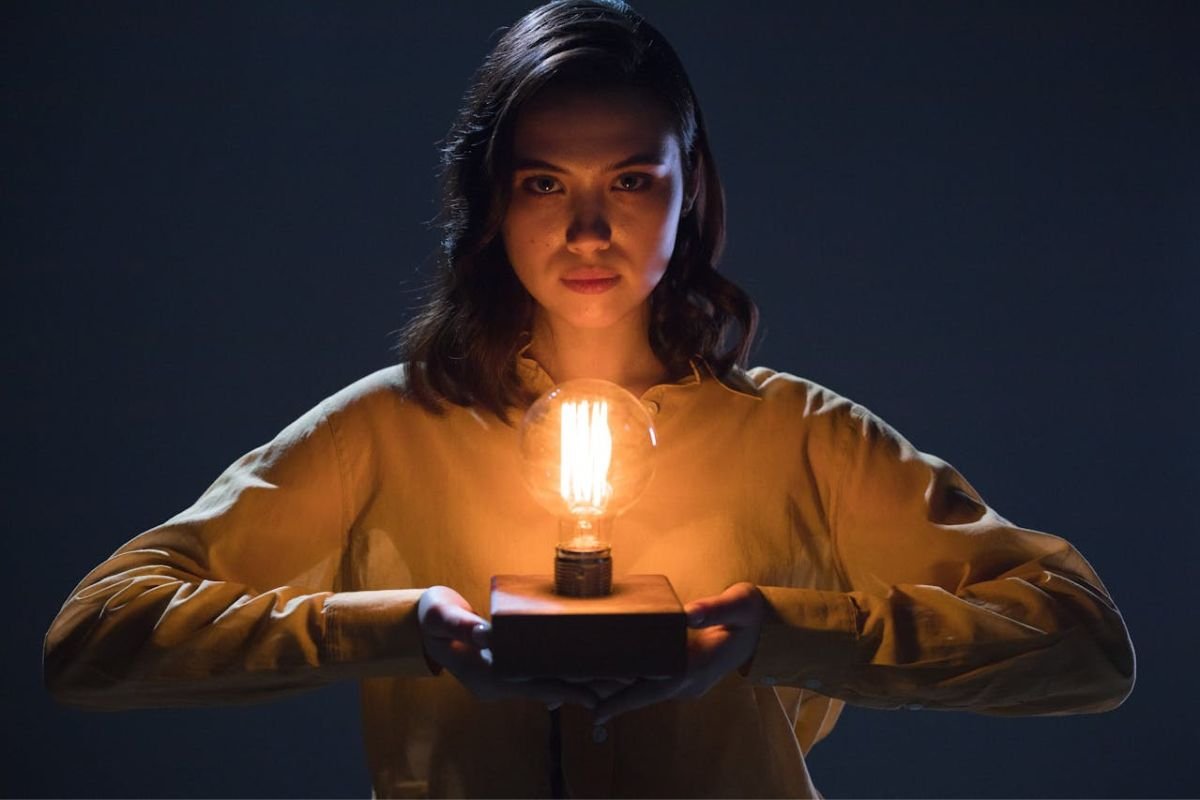 Highlighting Electrical Risks in Psychological Experiments A woman holding an incandescent light bulb, symbolising awareness of electrical dangers in the context of psychological experiments.