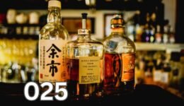 Three assorted liquor bottles on a table, symbolising the human relationship with alcohol through history.