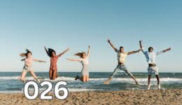A group of five diverse friends jumping in joy on a sandy beach under a sunny sky, celebrating companionship.