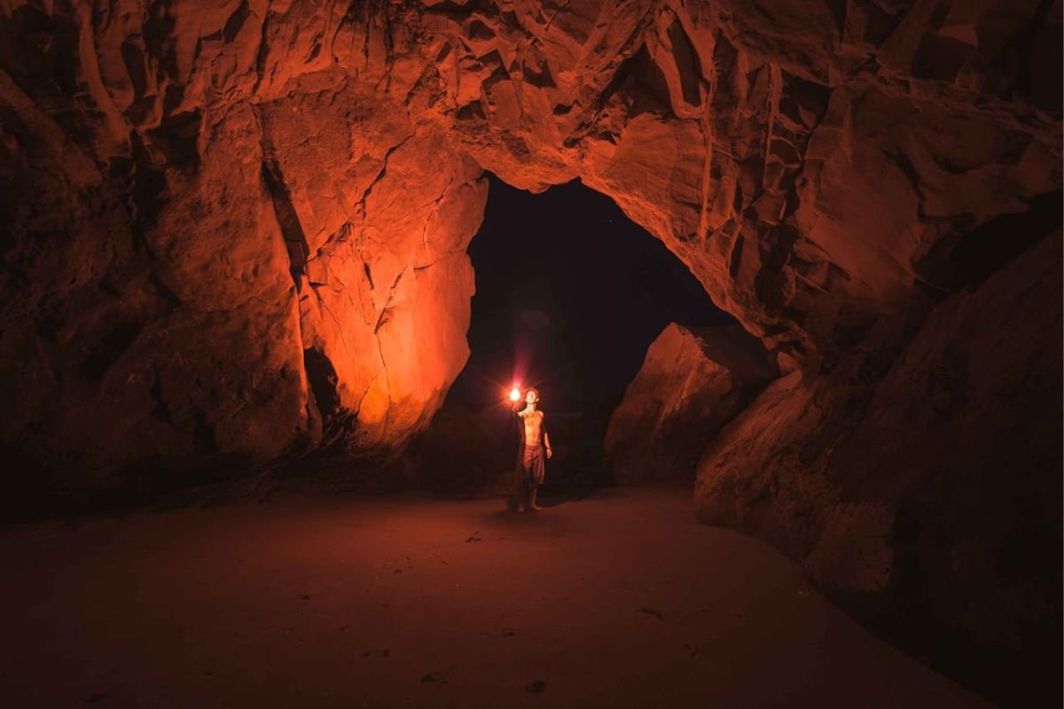 Resilience in the Darkness: A Person Holding a Lamp Inside a Cave A person holding a lamp inside a dark cave, symbolising resilience and hope in navigating challenges, inspired by the tale of the merchant and bandit.