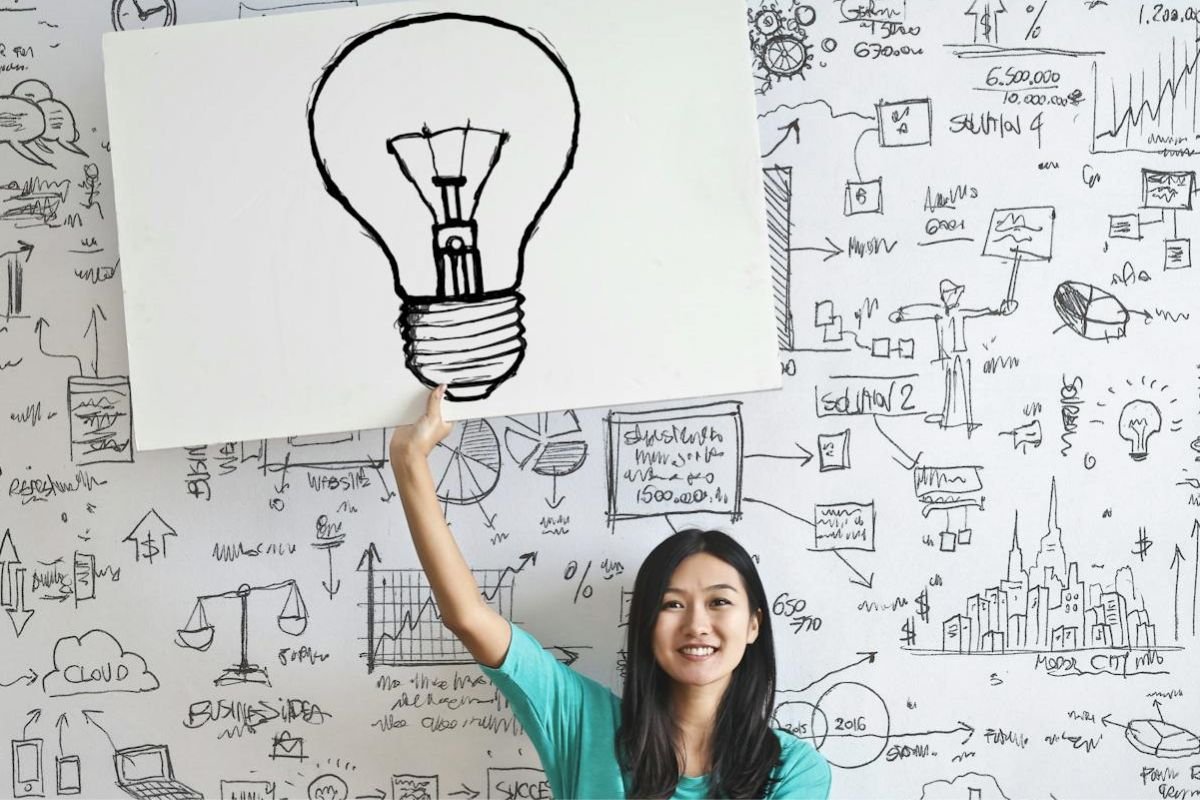 The Role of Alcohol in Unlocking Creativity: Insights and Inspiration A woman drawing a light bulb on a whiteboard, symbolising inspiration and the potential influence of alcohol on creativity.