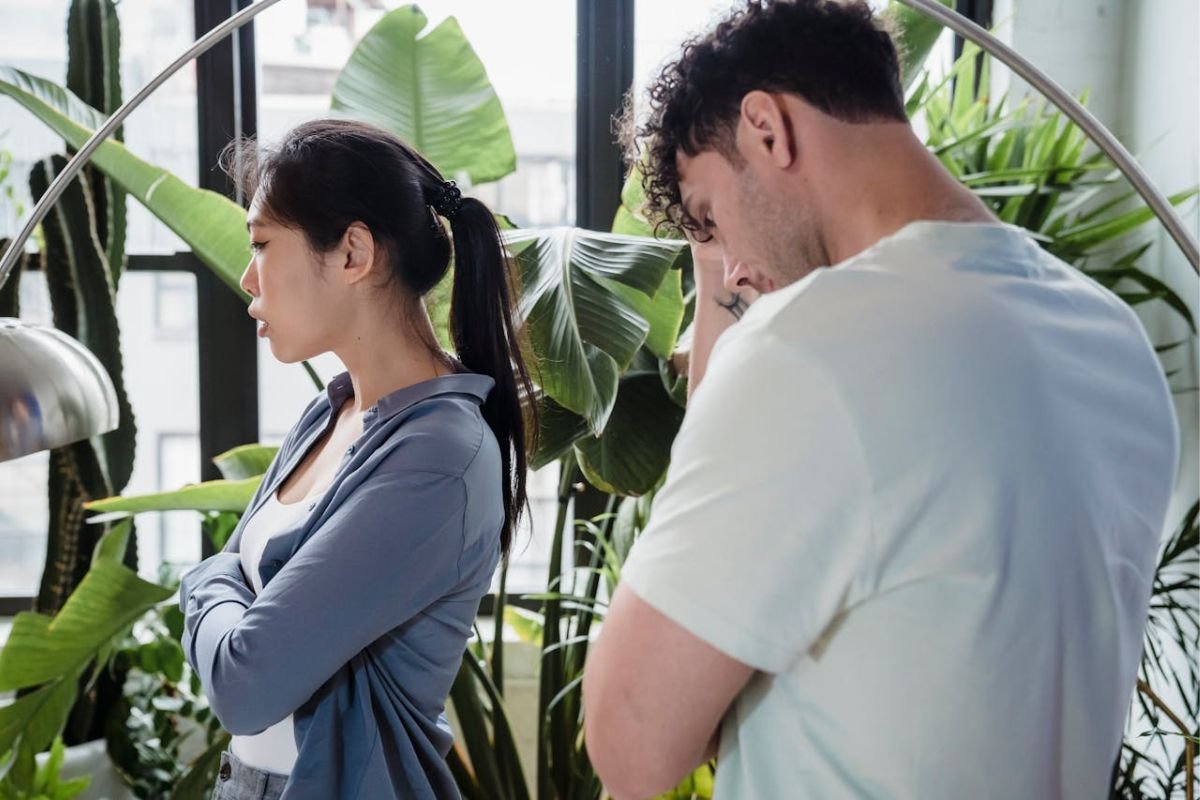 A man and woman standing apart with their arms crossed, signalling discomfort, nervousness, or a subconscious protective barrier during an argument.