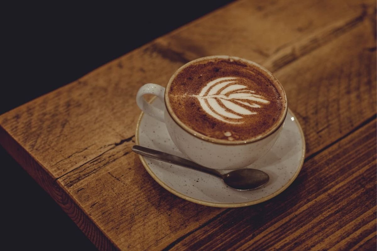 Steaming Cup of Coffee with Bokeh Lights in the Background A steaming cup of coffee in a white ceramic mug placed on a saucer, with blurred bokeh lights in the background.