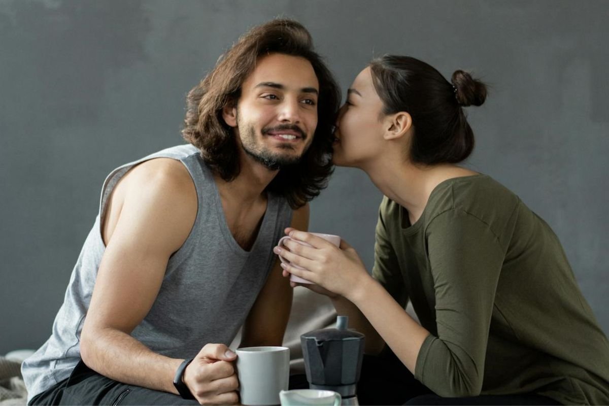 Whispering Close: A Body Language Cue for Genuine Connection A couple leaning close, with the woman whispering into the man’s ear, signalling genuine interest and a desire for connection.