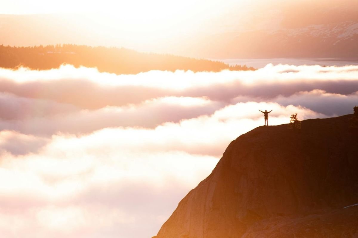 Embracing Growth: Resilience and Limitless Possibilities from the Mountain Peak A person standing atop a mountain peak, gazing at the vast horizon, symbolising growth, resilience, and life’s limitless possibilities.