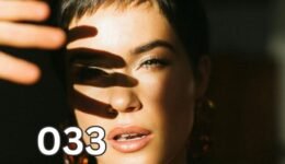 A woman with short hair shields her face from bright sunlight with her hand, casting a shadow of four fingers on her skin—symbolising the overwhelm highly sensitive people (HSPs) experience with bright lights and the four defining traits of HSPs.