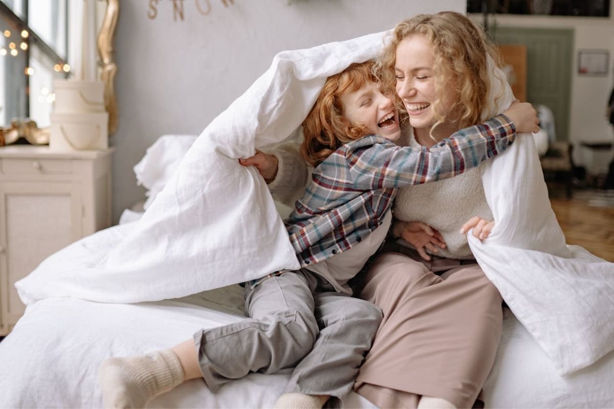 A Mother's Love: Protecting and Embracing Her Child Mother and child share a joyful moment wrapped together in a cozy blanket.