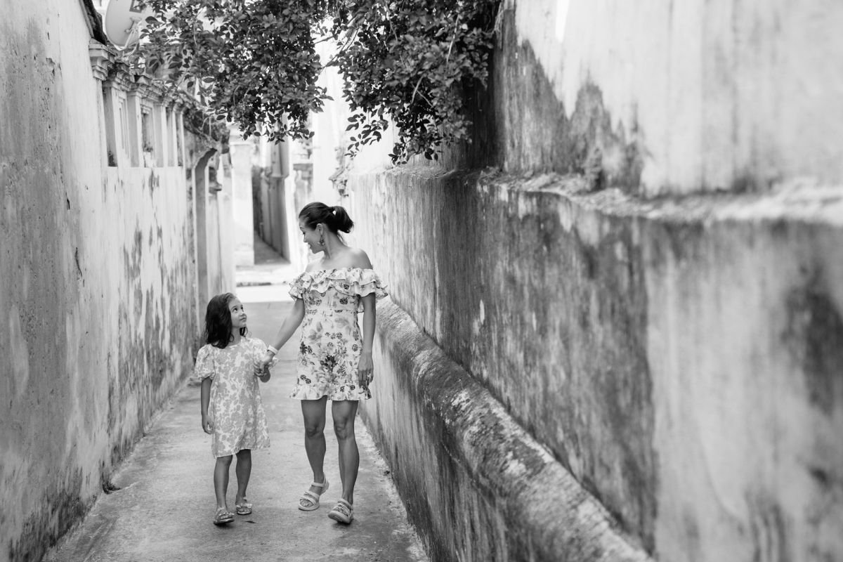 A Mother’s Pride Rooted in Presence, Not Achievement Young girl walks hand-in-hand with her mother down a quiet sidewalk, symbolising pride rooted in presence, not performance.