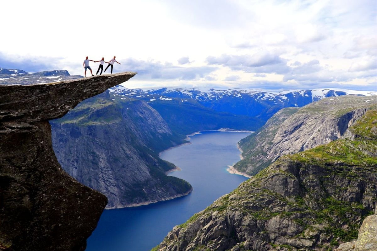 Standing Strong Together: The Three Traits That Shape a Powerful Mindset Three people holding hands on a cliff, symbolising unity, vision, and responsibility, the three traits of a strong mindset.