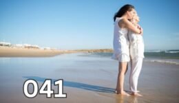 Elderly mother and adult daughter hugging affectionately on the beach, symbolising a deep, loving bond across generations.