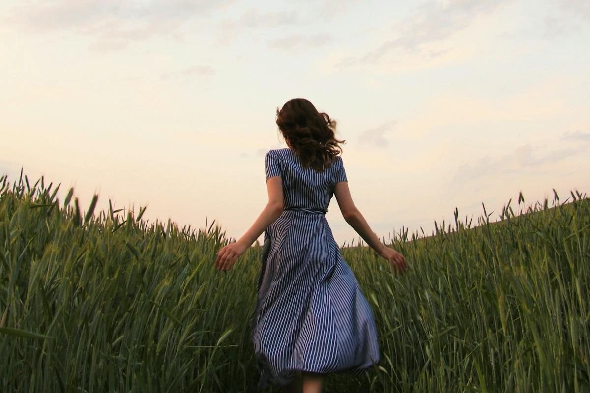 Running Toward Freedom and Energy Renewal Woman running freely through a grassy field, viewed from behind, symbolising the freedom of walking away from draining environments.