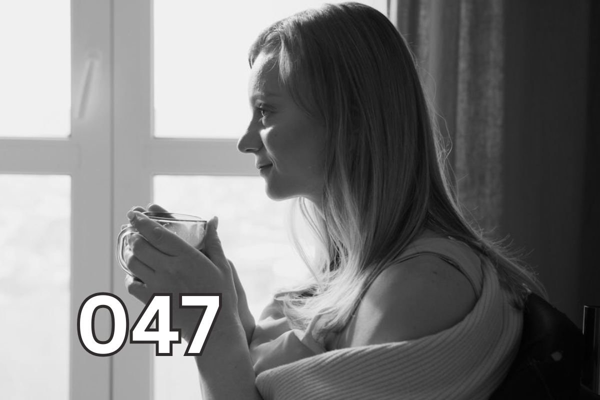 Thoughtful woman holding coffee mug, gazing into distance in grayscale photo