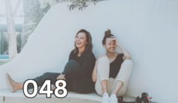 Two women laughing and bonding on a bench, symbolising instant connection and likability through shared joy and presence.
