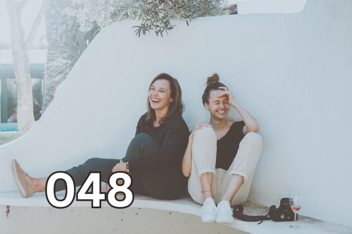 How Shared Joy Builds Instant Likability – Two Friends Laughing Together Two women laughing and bonding on a bench, symbolising instant connection and likability through shared joy and presence.