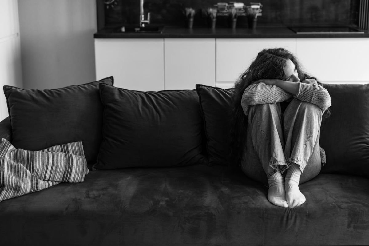 You Don’t Have to Explain Your Tiredness Woman sitting quietly with her head on her knees, conveying emotional overwhelm and silent exhaustion