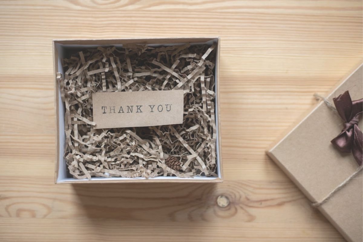 The Rule of Reciprocity – How Kindness Sparks Connection and Likability A small open gift box with a handwritten ‘Thank You’ card, symbolising the Rule of Reciprocity in human relationships.