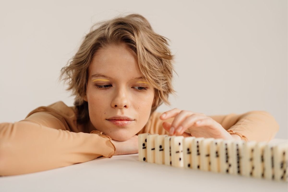 The Ripple Effect - One Small Act Can Change Everything Woman poised to tip dominoes, symbolising ripple effect of kindness and small actions creating big impact