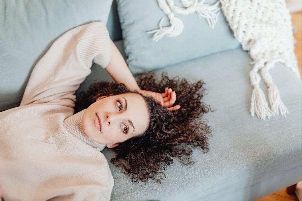 The Quiet Strength of Self-Regulation Calm woman resting on a sofa, looking off into the distance, reflecting on inner peace and emotional self-regulation