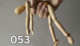 Hand holding a wooden mannequin like a puppet, symbolising emotional manipulation and control in relationships.