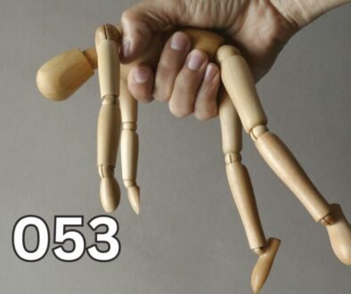 Hand holding a wooden mannequin like a puppet, symbolising emotional manipulation and control in relationships.