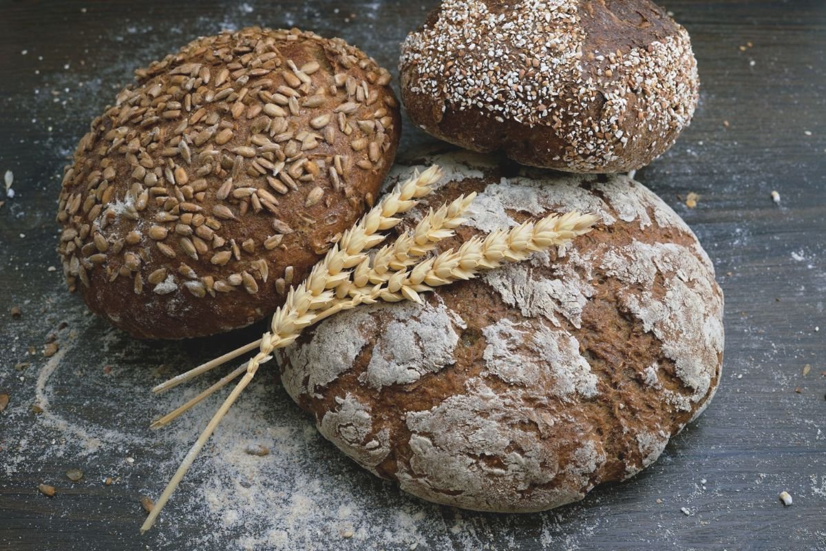 Wholemeal bread and wheat kernels on a rustic surface, representing the nourishing power of minimally processed wheat.