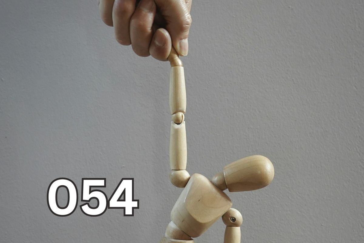 Puppet in Hand: Symbol of Emotional Manipulation and Control A wooden mannequin being controlled by a hand, symbolising emotional manipulation and loss of self-control.